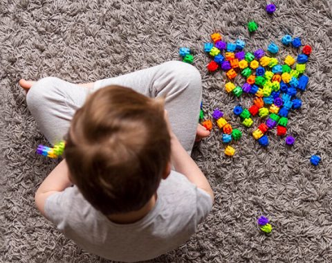 Un nen jugant amb boles de colors a terra.